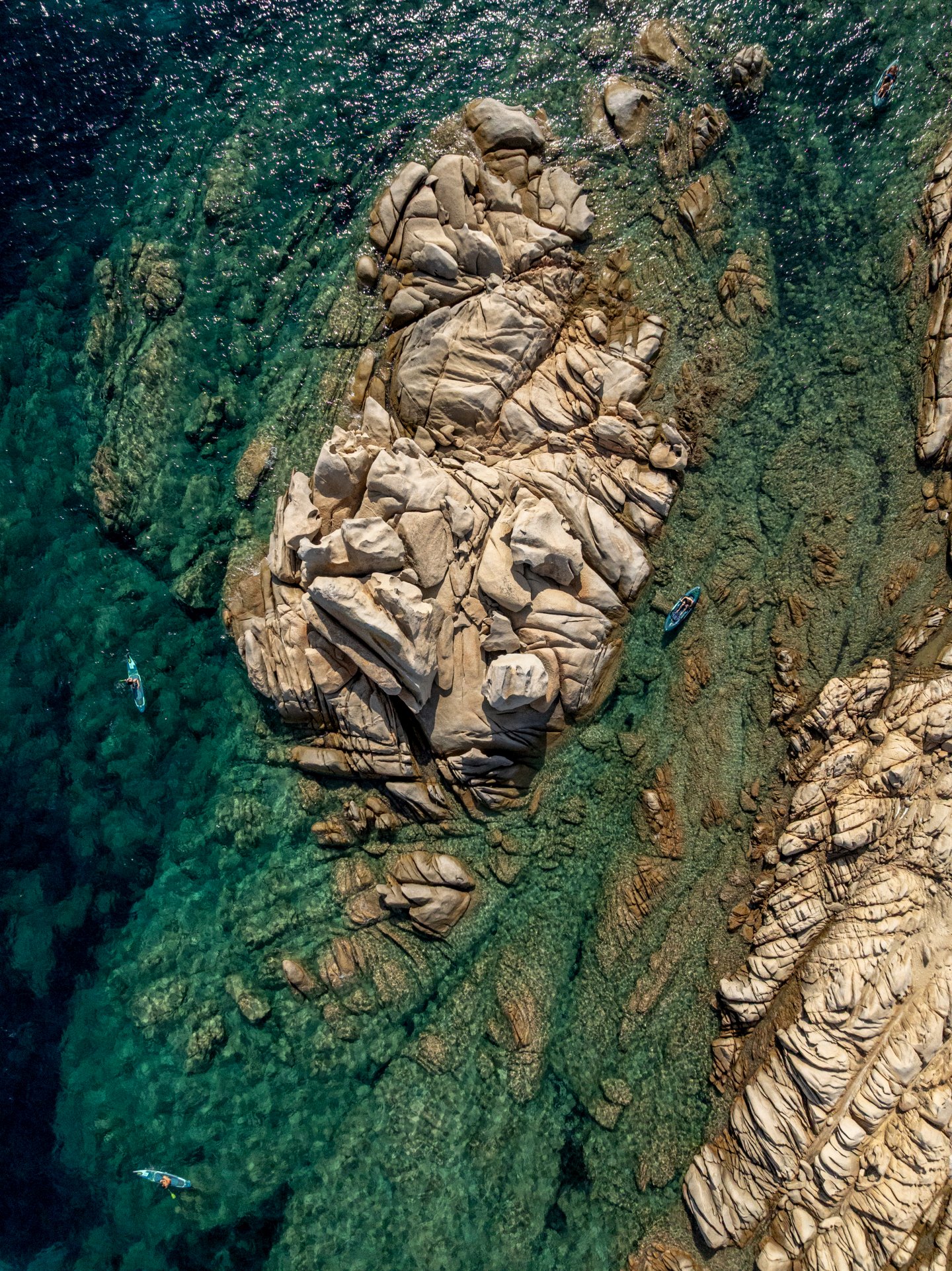 Kayak and paddleboard between granite rocks in clear water, seen from above
