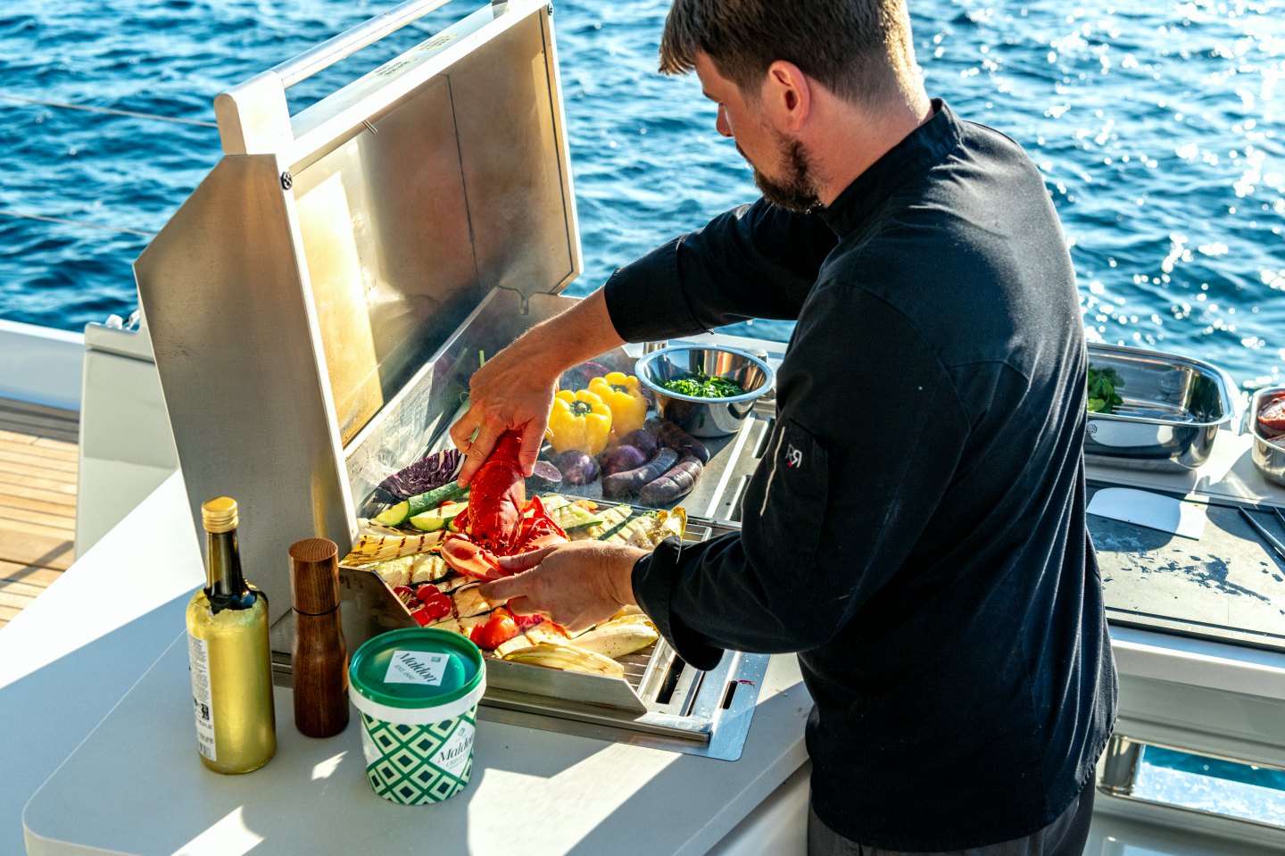Chef grilling lobster and vegetables in the outdoor galley