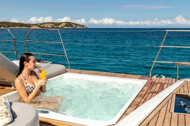 Guest with a cocktail in the Jacuzzi in the forward cockpit